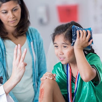 Young girl with head injury receiving medical attention from healthcare professional.