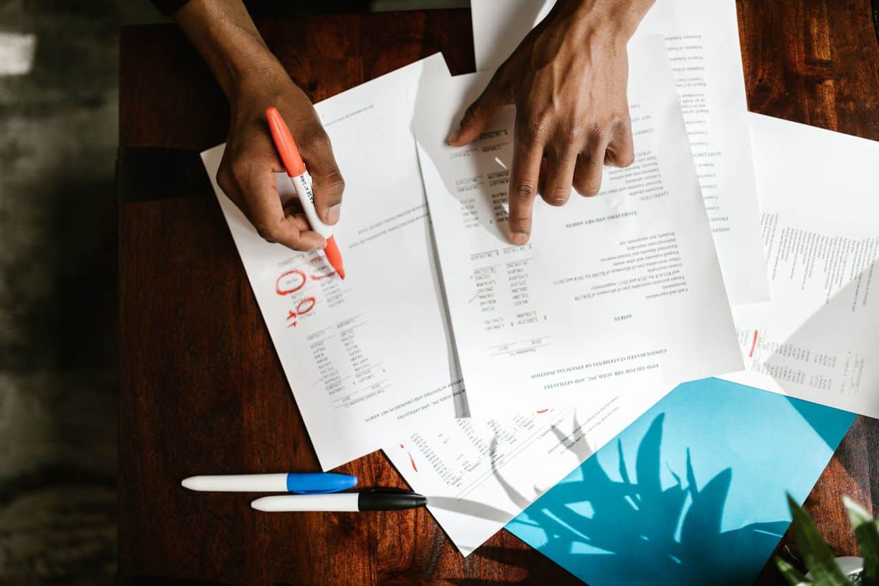 Two individuals reviewing and marking medical documents on a wooden table.